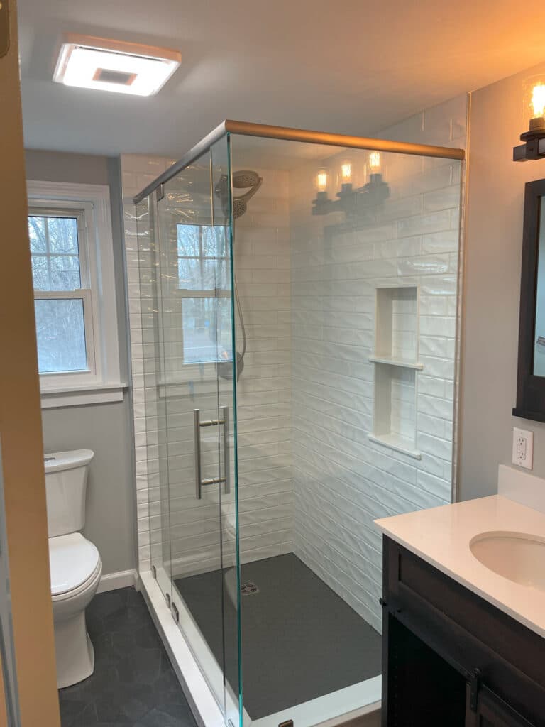 Glass-enclosed shower with white subway tiles and built-in wall niches.
